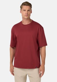 Rotes Kurzarm-T-Shirt aus weichem Material, mit Rundhalsausschnitt und lockerer Passform, versehen mit einem kleinen Logotag am Saum.