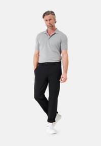 Grau Polohemd mit kurzen Ärmeln, kombiniert mit schwarzen Hosen und weißen Sneakern. Das Outfit zeichnet sich durch eine lockere Passform und eine glatte Textur aus.