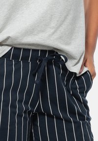 Marine gestreepte sweatpants van zacht materiaal, met een trekkoord in de taille, zijzakken en smalle witte verticale strepen.