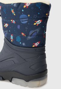 Bota de invierno de color azul oscuro con estampado espacial (cohetes, planetas). Cuenta con un suave forro de felpa blanca y suela de goma texturizada.