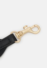 Schwarzer Lederarmband mit einem goldfarbenen Metallclip. Der Clip hat ein abgerundetes Ende und einen Federmechanismus für eine einfache Befestigung.