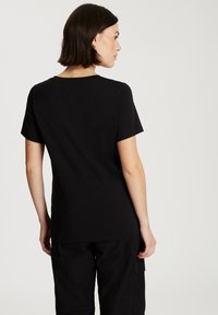 Czarny bawełniany t-shirt z okrągłym dekoltem, krótki rękaw i gładką teksturą, pokazany z tyłu z prostym, nieozdobionym wzorem.