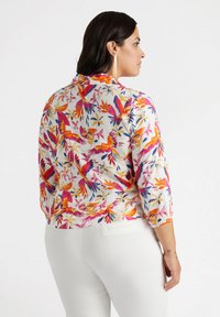Blusa floreale colorata con maniche a tre quarti, caratterizzata da una base bianca, motivi vibranti arancioni, rosa e blu, e orlo dritto.