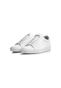 Baskets en cuir blanc avec une texture lisse, dotées d'un bout arrondi, de lacets plats et d'une semelle en caoutchouc texturée. Les détails d'accent comprennent des bords cousus.