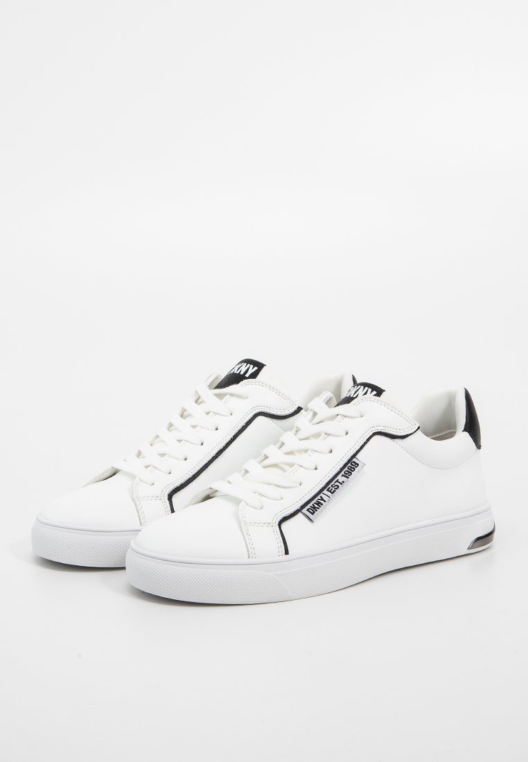 Witte leren sneakers met een gladde afwerking, zwarte accenten en een logo label. Voorzien van platte veters en een afgeronde neus. Rubberen zool.