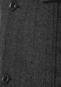 Donkergrijs visgraatweefsel met een gestructureerde afwerking, met een zwarte knoop als accent dicht bij de naad. Het ontwerp heeft een gestructureerde uitstraling.