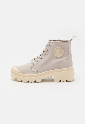 Bottines en toile beige clair avec embout en caoutchouc et semelle épaisse crème. Dotées d'un patch logo et d'une fermeture à lacets.