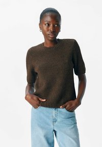 Bruin gebreid t-shirt met korte mouwen, een ronde hals en een gestructureerde afwerking, gecombineerd met lichtblauwe jeans.