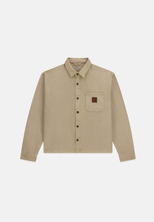 Beige blouse met lange mouwen, knopen, een kraag en een enkele borstzak met een klein bruin vierkant patch.