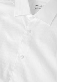 Camicia a righe bianche, vestibilità regolare, con una texture liscia, colletto a punta e chiusura a bottoni. Etichetta visibile nella zona del colletto.
