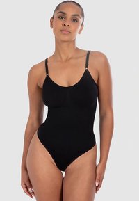 Czarny kombinezon z cienkimi, regulowanymi ramiączkami, z wycięciem w kształcie litery U, wysokim wycięciem na nogi i gładką fakturą materiału. Bez wzorów i ozdób.