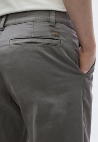 Γκρι, υφασμάτινο παντελόνι με υφή και ραμμένη εφαρμογή. Διαθέτει πίσω τσέπη με ετικέτα λογότυπου «BOSS». Το υλικό φαίνεται απαλό και ανθεκτικό.