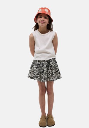 L'ensemble de vêtements comprend un haut sans manches blanc, une jupe à imprimé floral noir et blanc, et un chapeau seau à carreaux orange. Chaussures en daim marron.