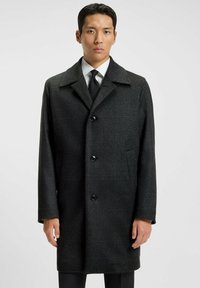 Cappotto di lana grigio a quadri con collo a punte, bottoni neri e due tasche laterali. Presenta un design a taglio dritto e un tessuto testurizzato.