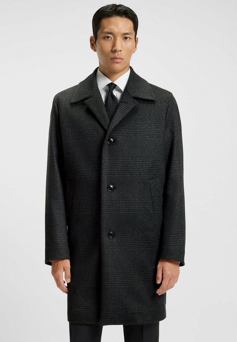 Cappotto di lana grigio a quadri con collo a punte, bottoni neri e due tasche laterali. Presenta un design a taglio dritto e un tessuto testurizzato.