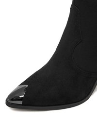 Must musta kreeniga saapad terava toes, millel on säravmust metallkatte detail lamedal taldal.