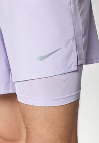 Licht paarse Nike-shorts met een zilveren logo, gemaakt van ademend materiaal, met een gladde textuur en een aansluitende binnenvoering.