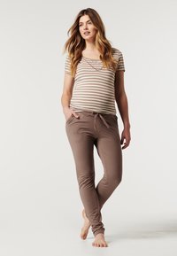 Camiseta de mangas curtas às riscas em bege e branco, combinada com calças de lounge em taupe com cordão. Tecido suave e corte descontraído.