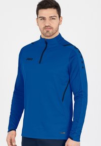 Giacca blu a maniche lunghe con zip a un quarto, logo nero, tessuto testurizzato e dettagli neri sulle spalle. Presenta dettagli con bottoni circolari.