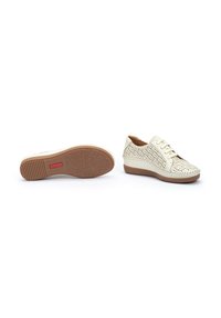Zapatos de cuero blanco perforado con suelas de goma marrón claro, con punta redonda, cierre de cordones y costuras decorativas a lo largo de los bordes.
