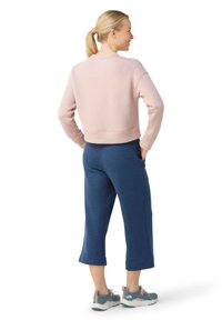 Lyserød cropped sweatshirt med ribbede manchetter, parret med marineblå cropped sweatpants og grå-blå sportssko med farverige accenter.