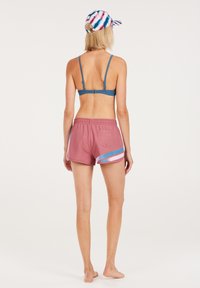 Blauwe bandeau bikini top met ribbelstructuur, gecombineerd met roze shorts met diagonale blauwe en roze strepen. Achteraanzicht getoond.