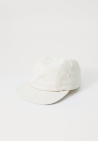 White cap made of cotton, featuring a low profile design, a curved brim, and vent holes on the sides for breathability.