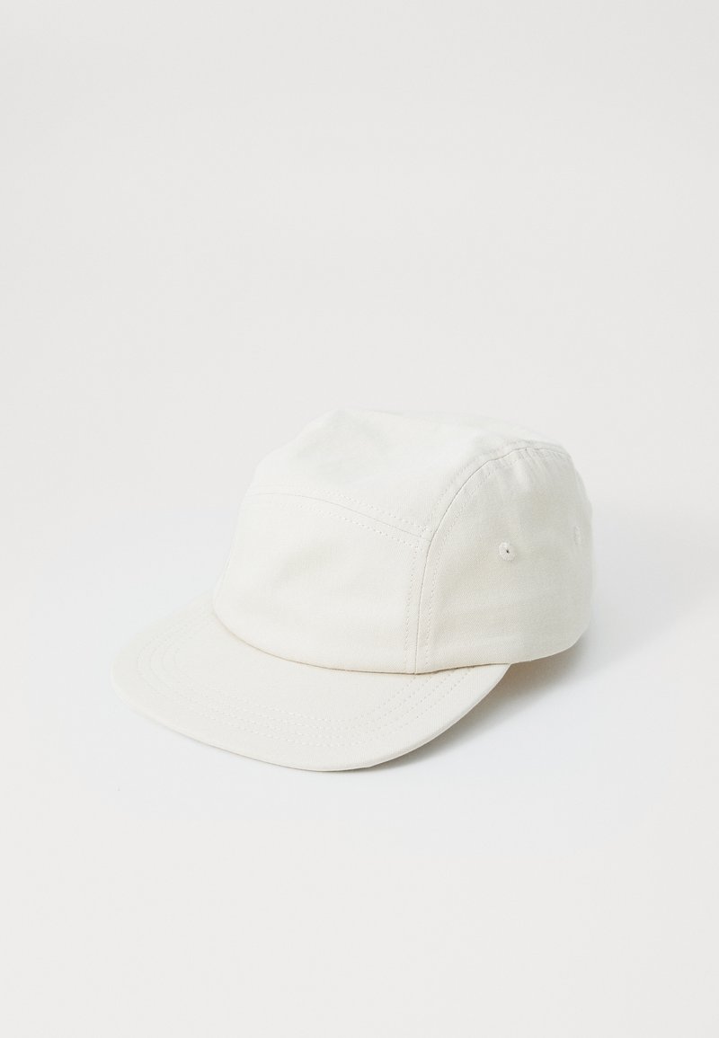 White cap made of cotton, featuring a low profile design, a curved brim, and vent holes on the sides for breathability.