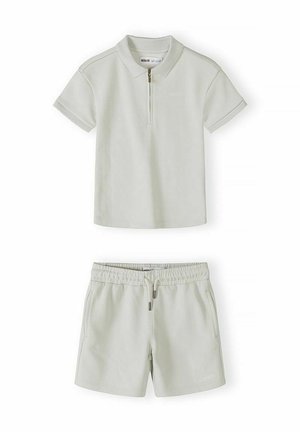 Kremowa koszulka polo z krótkim rękawem i zamkiem błyskawicznym oraz dopasowane szorty na elastycznym pasie ze sznurkiem i bocznymi kieszeniami.