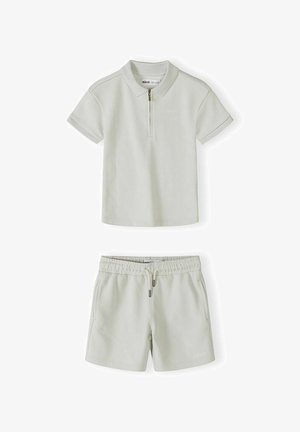 Polo manches courtes de couleur crème avec fermeture éclair et short assorti à taille élastique, cordon de serrage et poches latérales.