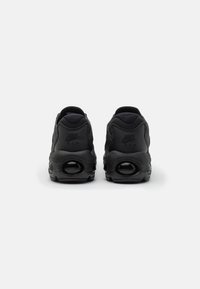 Baskets Nike Air noires avec une tige synthétique lisse, talon rembourré et coussin d'air visible dans la semelle. Détails subtils du logo.