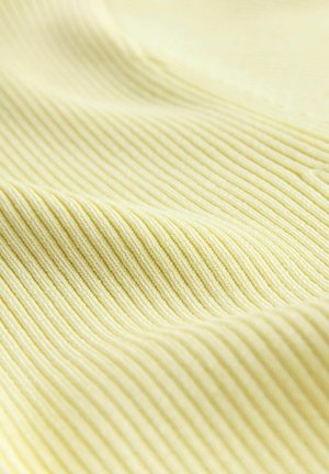 Detailný záber na jemnú, svetložltú rebrovanú tkaninu s jemnými záhybmi a textúrou.