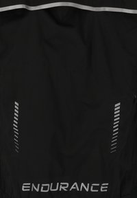 Svart tyg med reflekterande diagonala ränder på båda sidor och ordet "ENDURANCE" i reflekterande text längst ner.