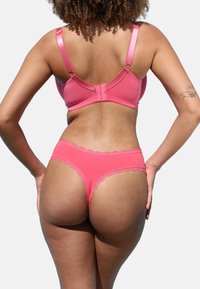 Pink lingerie set featuring a smooth fabric bralette with adjustable satin straps and matching lace-trimmed thong.
