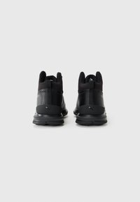 Czarne wodoodporne sneakersy za kostkę z fakturowanymi panelami, wyściółką w kołnierzu i gumową podeszwą. Zawierają logo na pięcie i z tyłu buta.