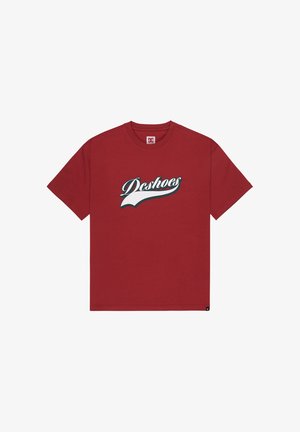 Rotes Baumwoll-T-Shirt mit dem "DC Shoes"-Logo in Weiß und Blau in Kursivschrift, Rundhalsausschnitt, kurzen Ärmeln und geradem Saum.