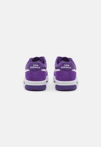 Sneakers in suede viola con dettagli bianchi. Presentano un marchio prominente sul tallone, una soletta imbottita e una suola in gomma testurizzata.