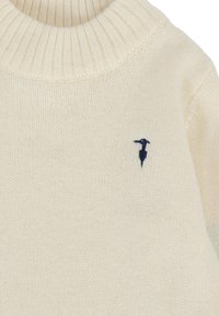 Maglione color crema con colletto a coste, motivo a maglia testurizzato e un piccolo logo blu marino sul petto.