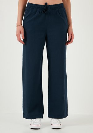 Wide-leg, navy blue pants with a drawstring waistband, made of a soft fabric, featuring a relaxed fit and minimal seams.