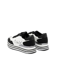 Zwart-witte sneaker met een bovenwerk van leer en stof, voorzien van een gelaagde zool met zilveren accenten en een logo aan de zijkant.