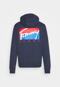 Marineblauer Hoodie mit einem rot-weißen-blauen Grafikmotiv auf der Rückseite, das den Text "Tommy Jeans" zeigt. Das Material ist wahrscheinlich eine Baumwollmischung mit einer weichen Textur.
