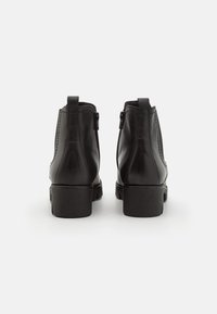 Botines de cuero negro con textura suave, punta redondeada y tacón bajo de bloque; cuentan con cierres laterales con cremallera y tiras para tirar en la parte trasera.