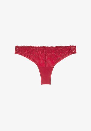 Tanga rojo con detalles de encaje en la cintura, cuerpo de tela suave y bordes lisos. La parte trasera es semitransparente con un panel sólido.