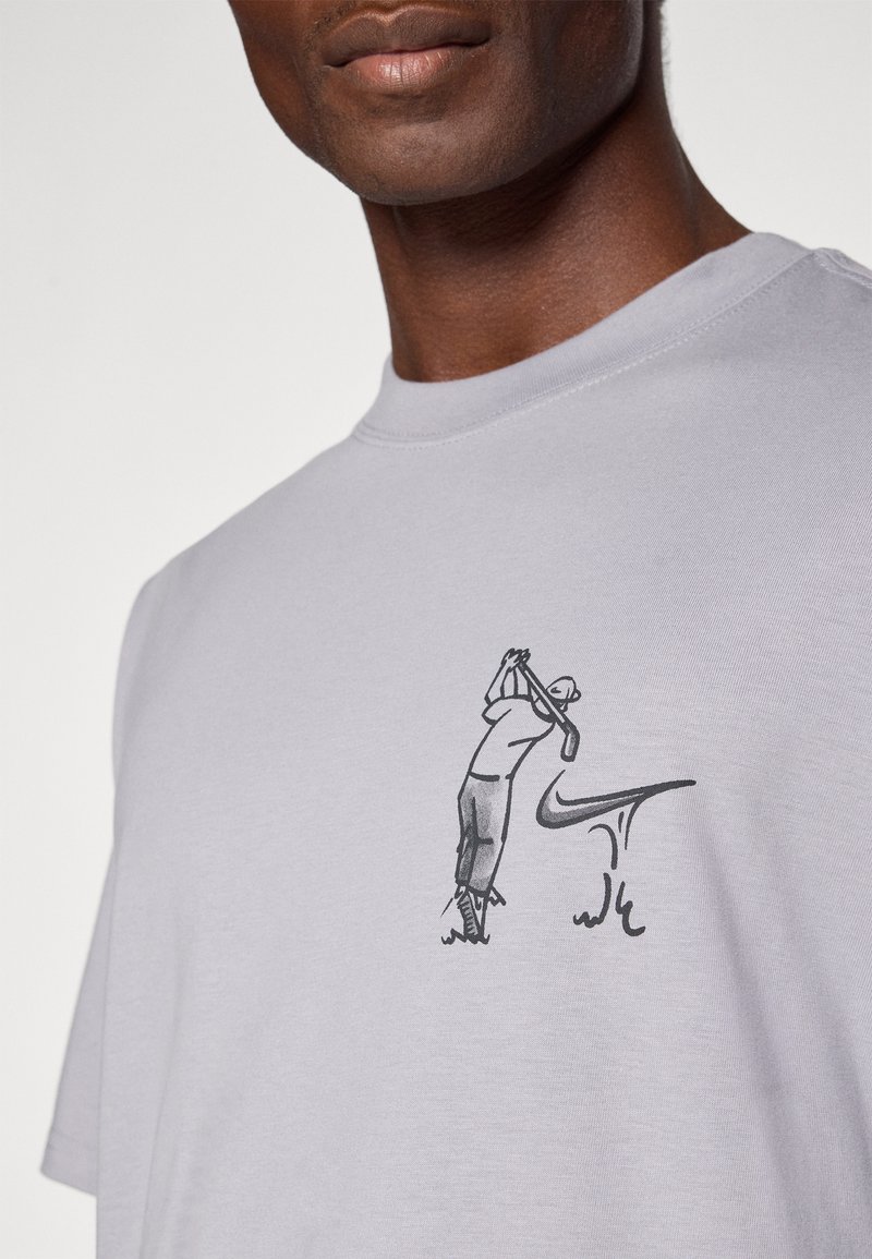 Light grey cotton t-shirt featuring a black graphic of a golfer in action, with a stylized Nike logo integrated below the figure.