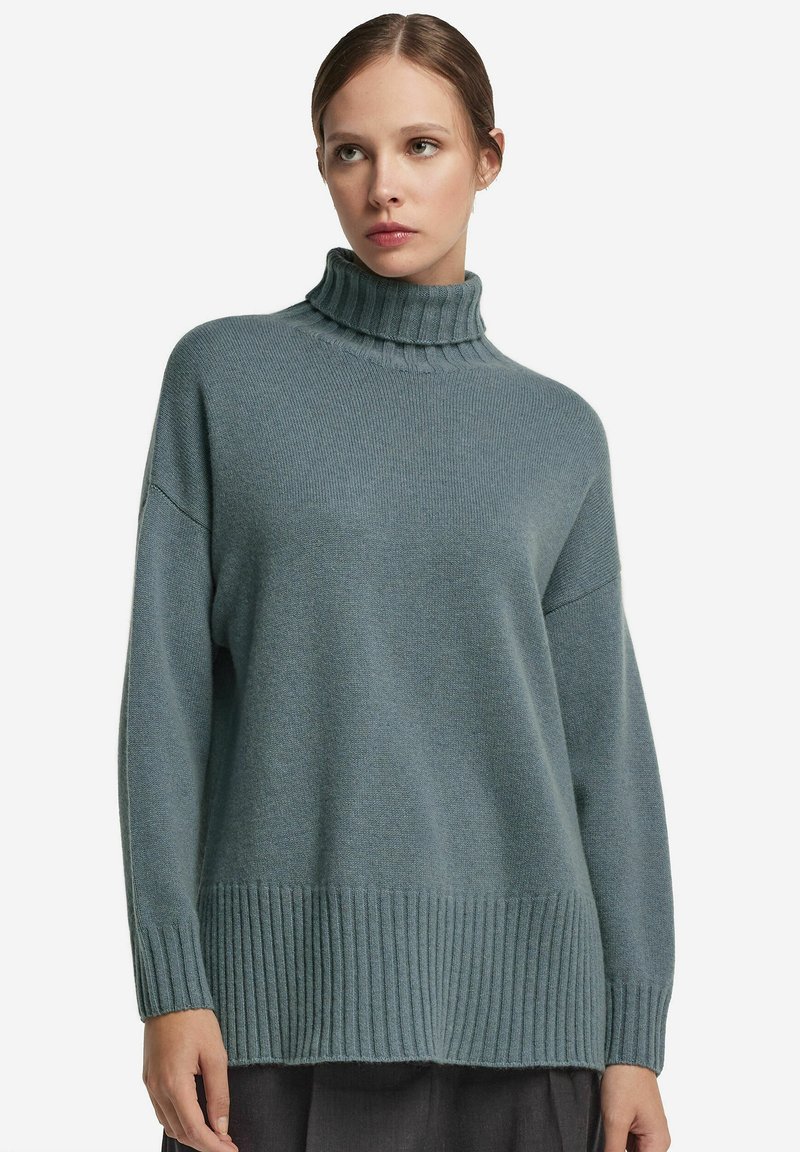 Överdimensionerad polotröja i mjuk teal, med ribbade ärmslut och fåll. Tillverkad av texturerad stickad tyg för en bekväm passform.