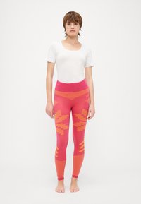 Fitted pink leggings with geometric orange patterns, ribbed waistband, and textured accents. Designed for comfort and stretch.