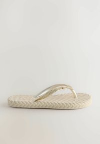 Flip-Flop-Sandale mit einer geflochtenen beigen Sohle und metallisch goldenen Riemen mit einer glatten, glänzenden Oberfläche. Einfaches und minimalistisches Design.