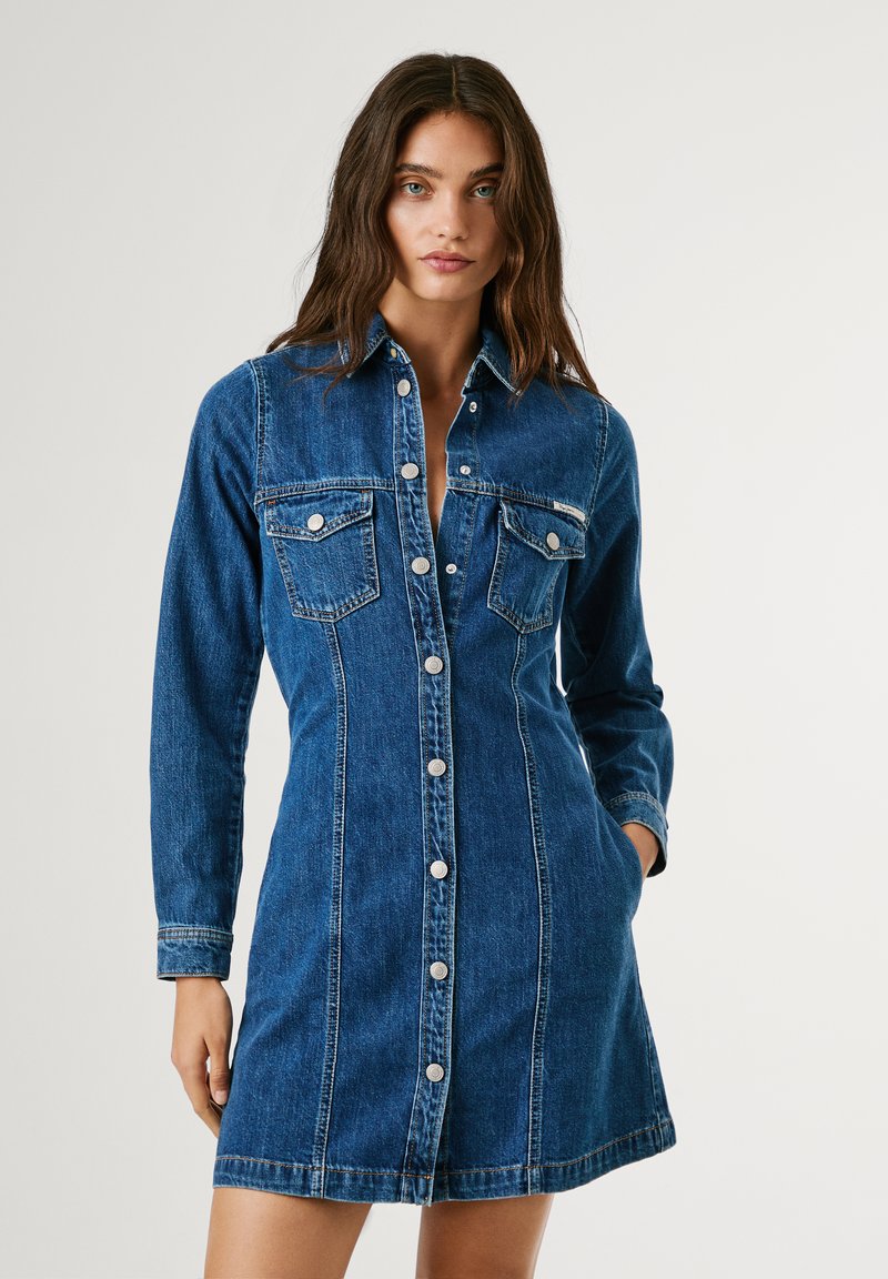 Robe chemise en denim bleu foncé, dotée de manches longues, d'une fermeture à boutons, de deux poches poitrine et d'une silhouette ajustée avec des détails de couture.