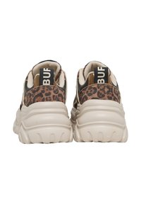 Ζεύγος chunky sneakers με παχιές λευκές σόλες, λεπτομέρειες σε λεοπάρ μοτίβο και μαύρα κορδόνια με την ετικέτα "BUF" σε μπεζ εσωτερικούς χώρους.