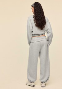 Gray cropped sweatshirt and matching wide-leg sweatpants, featuring a relaxed fit and ribbed waistband, paired with light sneakers.